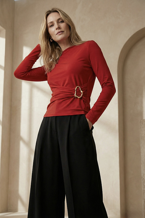 Червоний лонгслів з асиметричною лінією пояса та декоративною пряжкою.